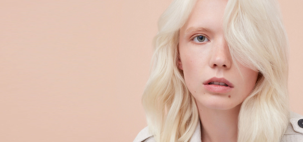 Person with light blonde hair against a beige background